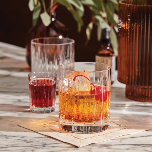 Crystal glasses with cocktails on a marble table, garnished with a cherry.